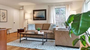 A living room with a sofa, coffee table, and a painting on the wall. - Mellow Yellow | UW & Children's | Backyard Patio! (Seattle)