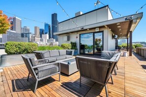 A rooftop terrace with a modern outdoor seating area, including a sofa and chairs, and a view of the city skyline in the background. - Live & Work! | Waterfront views + Prime DT | Fast Wi-fi (Seattle)
