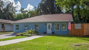 A single-story house with a blue exterior, a front porch, and a wooden fence.