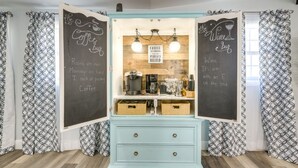 Una cocina con un menú en una pizarra, una cafetera y una encimera de madera.
