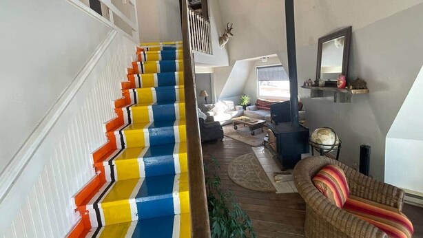 A staircase with colorful steps, a living room with a sofa and a fireplace, and a dining area with a table and chairs. - Dome house in Centennial valley (Laramie)