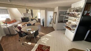 A spacious living area with a dining table, chairs, and a red patterned rug. There is a kitchen area with white cabinets and a black refrigerator. - Dome house in Centennial valley (Laramie)
