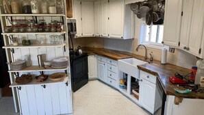 A kitchen with white cabinetry, a wooden countertop, and various kitchen utensils and appliances. - Dome house in Centennial valley (Laramie)