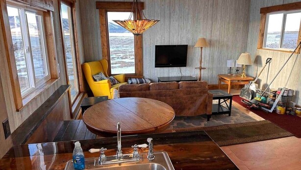 Ein gemütliches Wohnzimmer mit Holzboden, einem runden Couchtisch, einer Couch und einem an der Wand befestigten Fernseher.