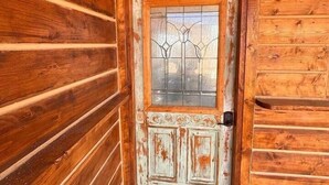 Eine Holzhütte mit einer rustikalen Tür, die ein Glassfeld und einen Metallgriff aufweist.