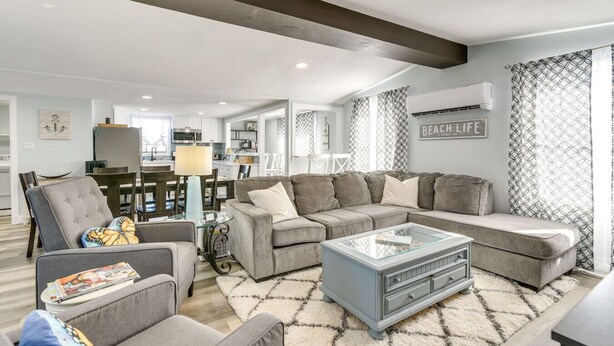 A modern living room with a sectional sofa, a glass coffee table, and a dining area in the background. - Galveston Beach Retreat | Balcony & Walk to Seawall (Galveston)