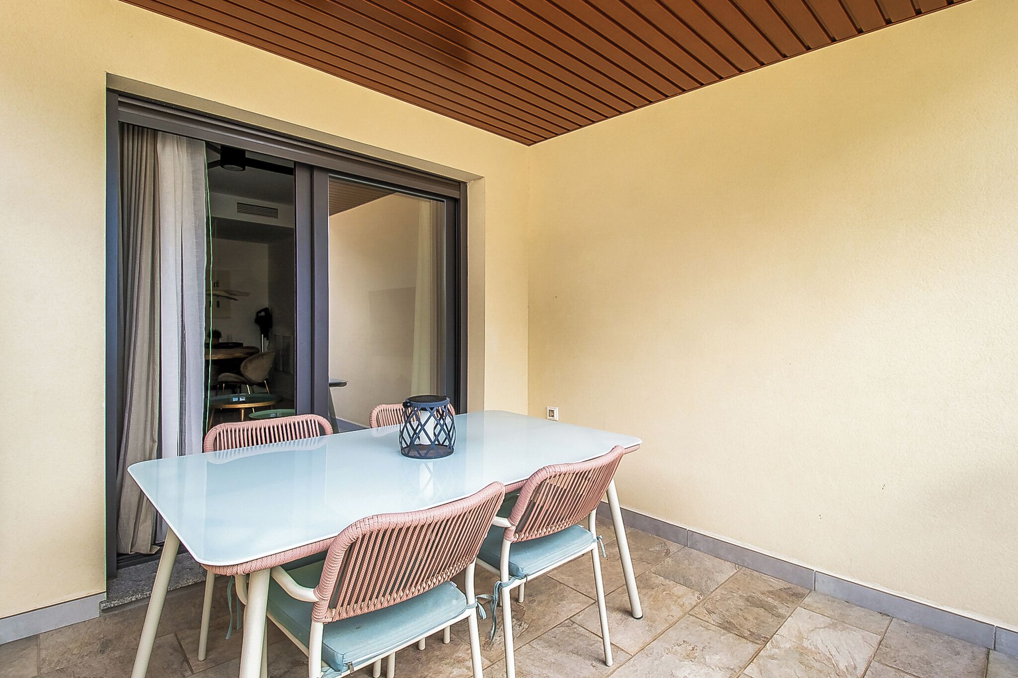 A dining area with a table and chairs, a sliding glass door, and a ceiling with wooden slats.