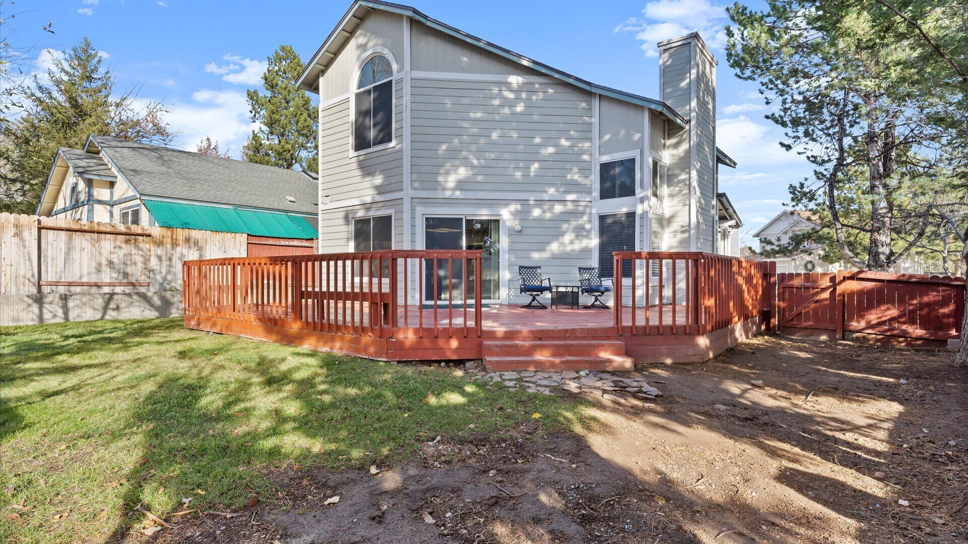 A two-story house with a deck and a fenced backyard.