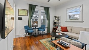Un salon avec un ventilateur de plafond, un canapé, une table basse et deux fauteuils bleus.