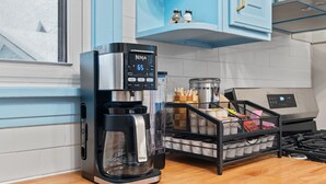 Une cuisine équipée d’une machine à café, d’une cuisinière et d’une fenêtre.