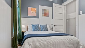 Une chambre à coucher avec un lit, une table de chevet, une lampe et une porte.