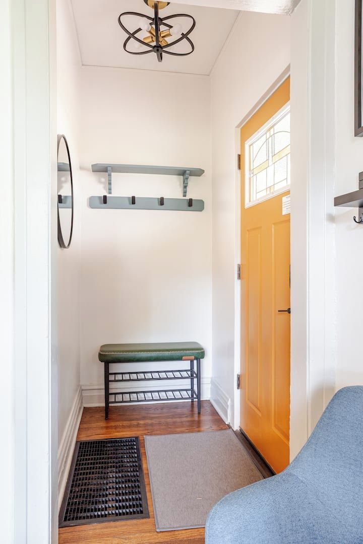 Un couloir avec un banc, une porte, un luminaire au plafond et une grille d’aération.