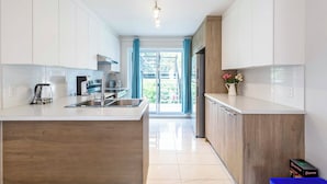 A modern kitchen with white cabinetry, a stainless steel sink, and a built-in oven. - 10-Min La Ronde Ride! Cozy Place, Free Parking! (Longueuil)