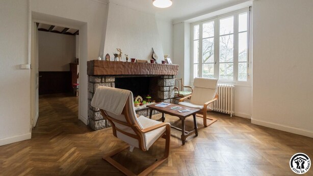 A living room with a fireplace, wooden flooring, a table with magazines, and a window with a view. - Chez Marius - ESTENOS (ESTENOS)