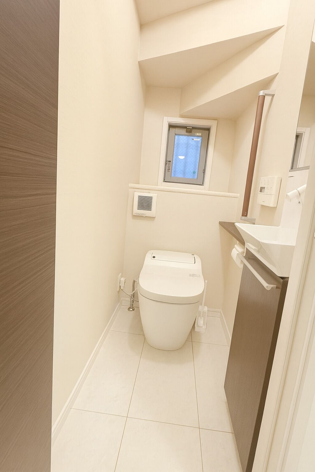 Un bagno piccolo e moderno con il water, una finestra e uno specchio.
