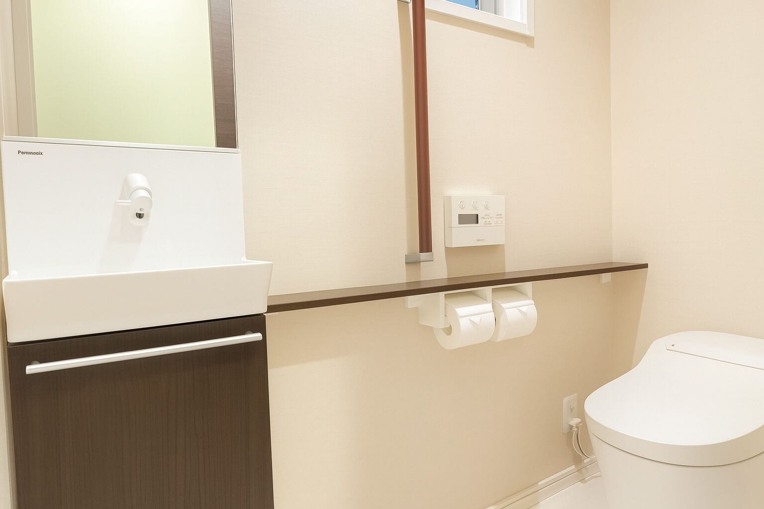 A bathroom with a toilet, a sink with a mirror, and a paper towel dispenser.
