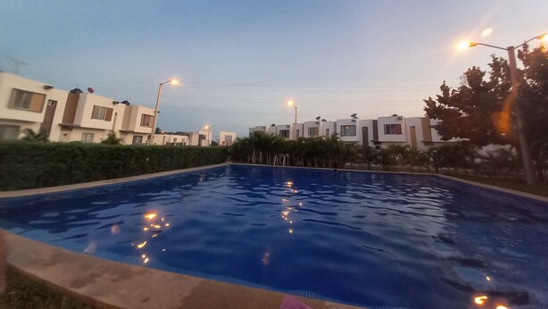 A swimming pool with a clear blue water surface, surrounded by modern buildings with flat roofs and satellite dishes. - Quiet house in gated community with A/C and Pool (Paseo de las Palmas II)