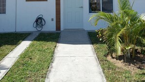 A modern two-story building with a white facade, wooden accents, and a number 168 door. - Quiet house in gated community with A/C and Pool (Paseo de las Palmas II)