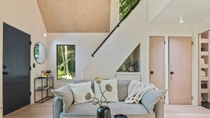 A modern living room with a grey sofa, a black vase, and a book on a wooden table.