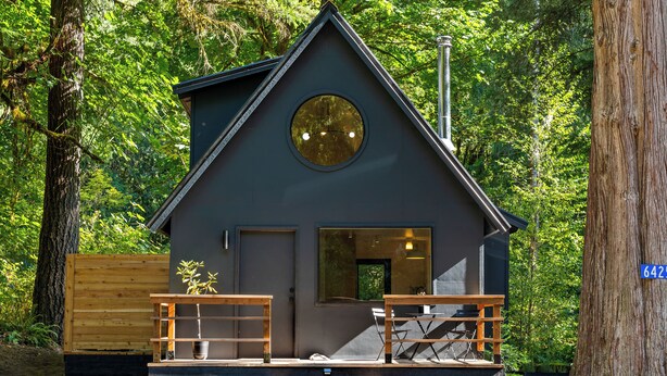 A small cabin with a wooden deck, a circular window, and a door.