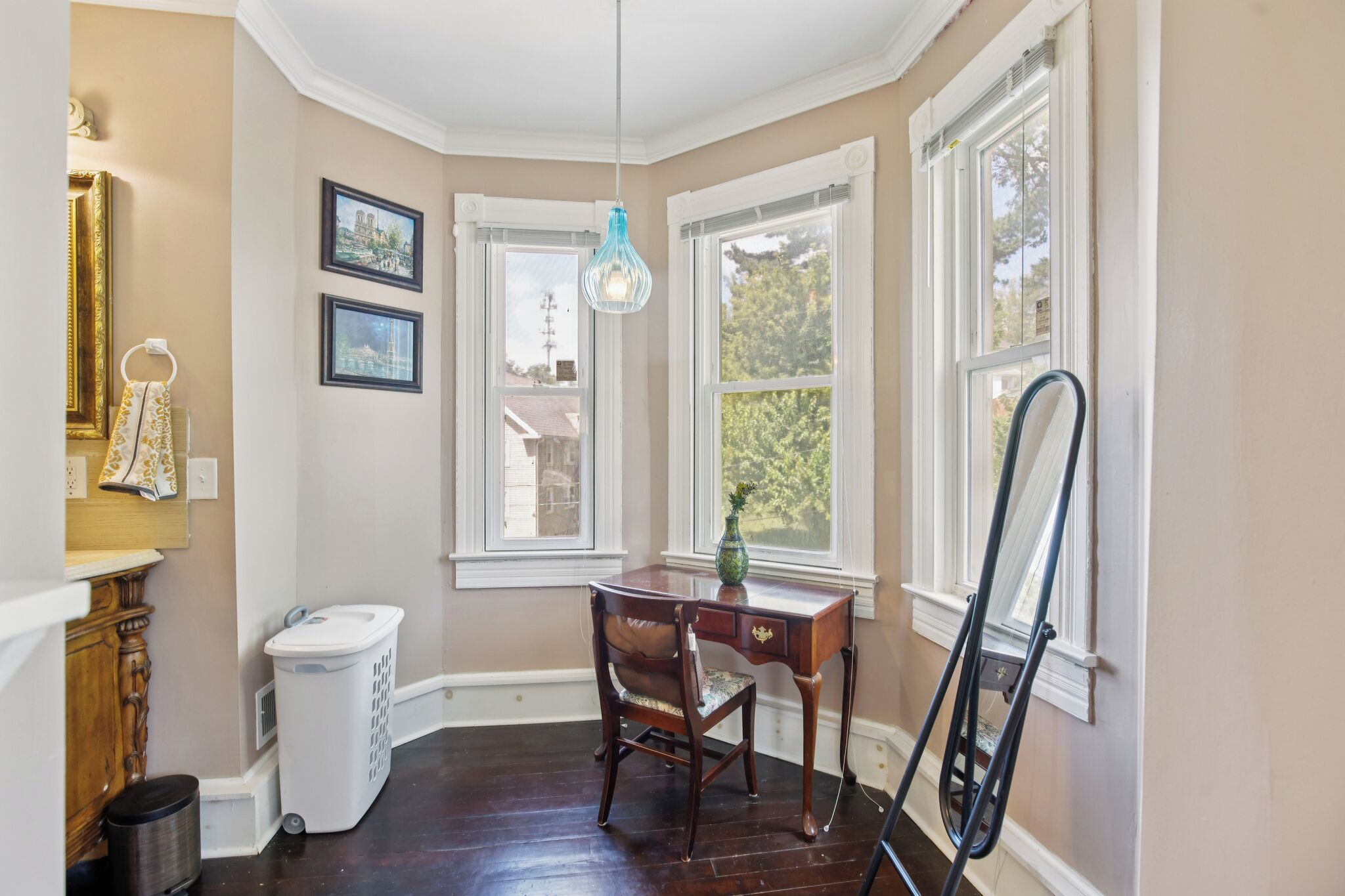 A corner room with a desk, chair, and a hanging light fixture.
