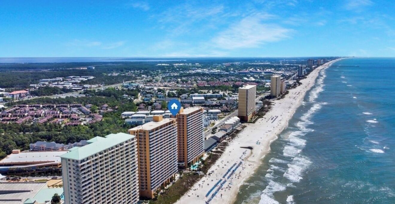 A coastal cityscape with high-rise buildings, a beach, and a clear sky.