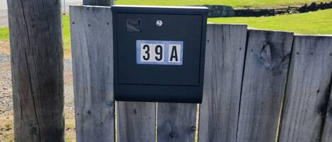 A wooden fence with a mailbox labeled "39A" and a utility pole.