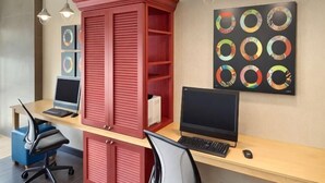 Un espacio de trabajo con dos escritorios, dos sillas, un armario rojo y una pared decorada con arte circular.