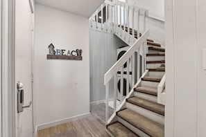 A staircase with white railings and beige carpeted steps. - Pet Friendly Steps to the Beach and Boardwalk Downtown Rehoboth Beach (Rehoboth Beach)