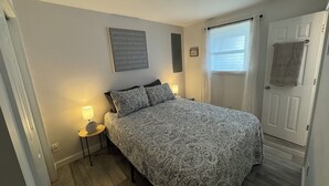 A bedroom with a bed, bedside lamps, a wall with motivational quotes, a window with curtains, and a door with a towel hanging on it. - Private, Cozy, Clean apartment in lovely Hyde Park (Hyde Park)