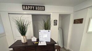 A bar area with a 'HAPPY HOUR' sign, two potted plants, a welcome sign, and a 'Love your family' sign on the wall. - Private, Cozy, Clean apartment in lovely Hyde Park (Hyde Park)