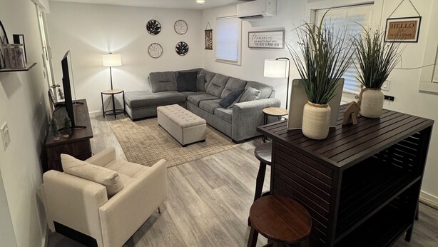 A modern living room with a sectional sofa, a coffee table, and a bar area with stools. - Private, Cozy, Clean apartment in lovely Hyde Park (Hyde Park)