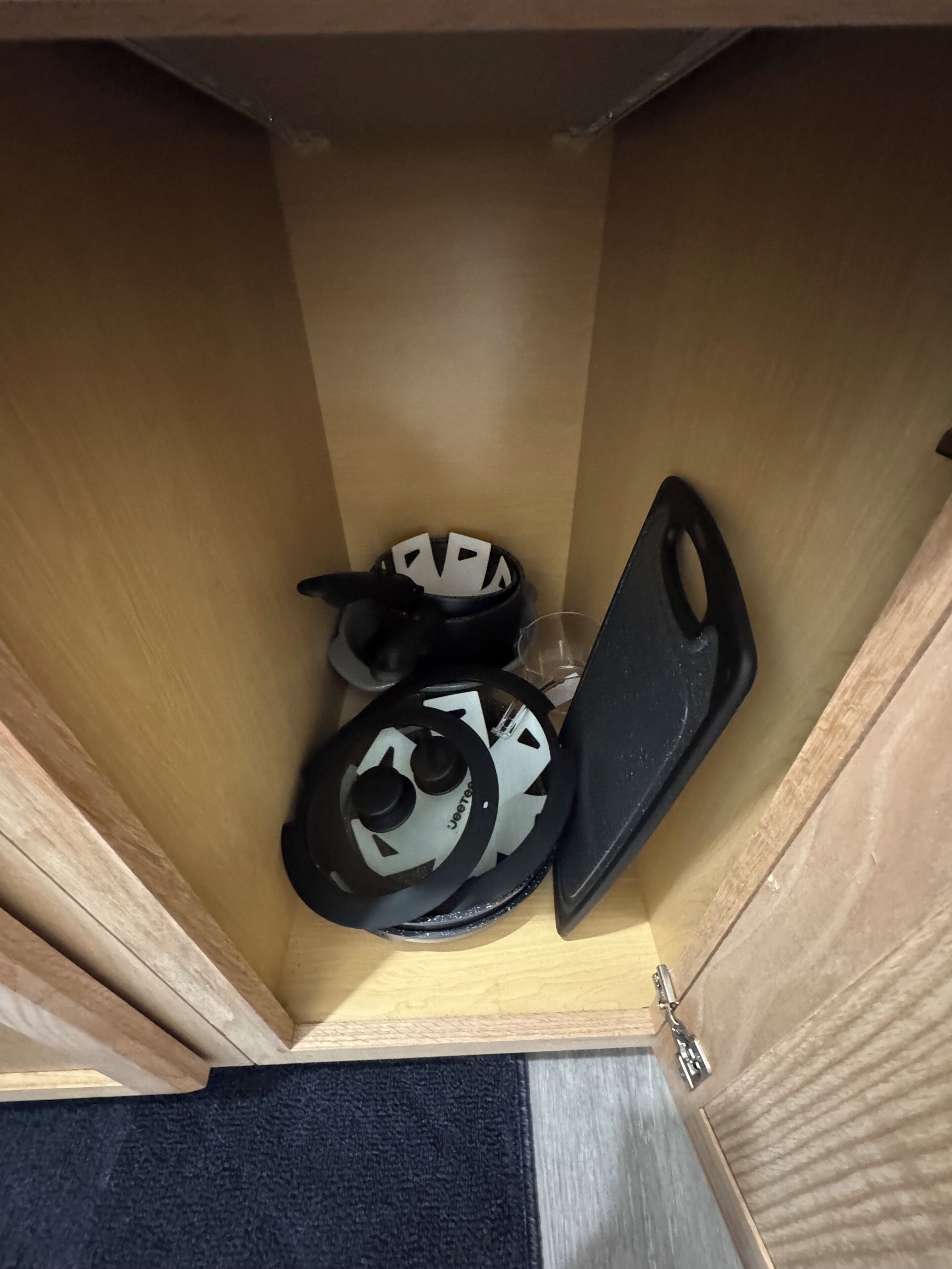 A storage space with a pair of black and white sandals, a black shoe, and a plastic container.