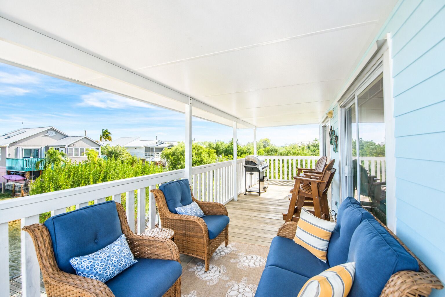 A covered porch with wicker furniture and a view of neighboring houses.