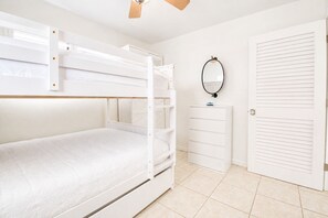 A bunk bed with a white headboard, a dresser with a mirror, and a white door with horizontal blinds. - Updated Canal Home with Dock for 25' Boat, Sandbar Access & Backcountry Fishing (Big Pine Key)