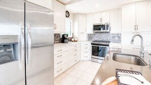 Una cocina moderna con electrodomésticos de acero inoxidable, armarios blancos y un salpicadero de azulejos.