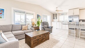 Un salón amplio con sofá, sillón, mesa de centro y vistas a la cocina.