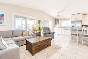 A spacious living room with a sofa, armchair, coffee table, and a view of the kitchen. - Updated Canal Home with Dock for 25' Boat, Sandbar Access & Backcountry Fishing (Big Pine Key)