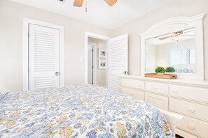 Ein Schlafzimmer mit Bett, Kommode und Spiegel.