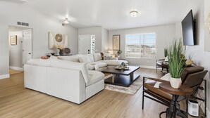 Una sala de estar moderna con un sofá modular, una mesa de centro y una zona de comedor con una silla y una mesa.