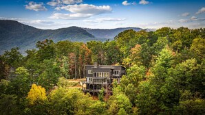 A modern two-story house surrounded by dense forest with a mountain backdrop. - Blue Ridge Mountain Retreat, Panoramic Views, Game Room, and Hot Tub! (Blue Ridge)