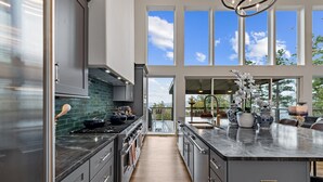 A modern kitchen with a central island, large windows, and a view of the outdoors. - Blue Ridge Mountain Retreat, Panoramic Views, Game Room, and Hot Tub! (Blue Ridge)