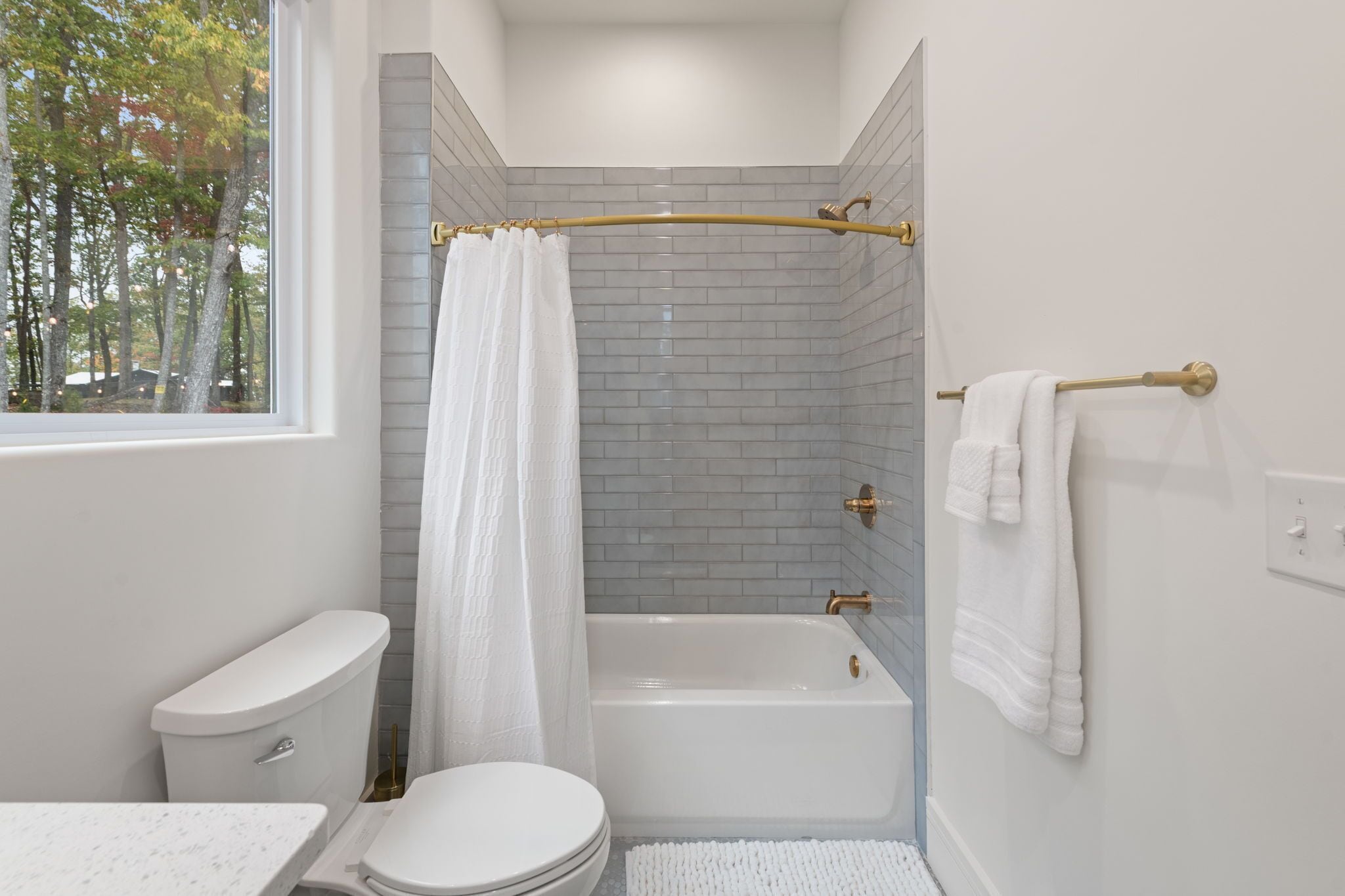 Een moderne badkamer met toilet, bad en douchegordijn.