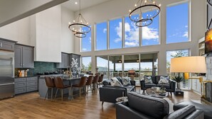 A spacious kitchen with a large island, bar stools, and a dining area with a black leather sofa and a coffee table. - Blue Ridge Mountain Retreat, Panoramic Views, Game Room, and Hot Tub! (Blue Ridge)