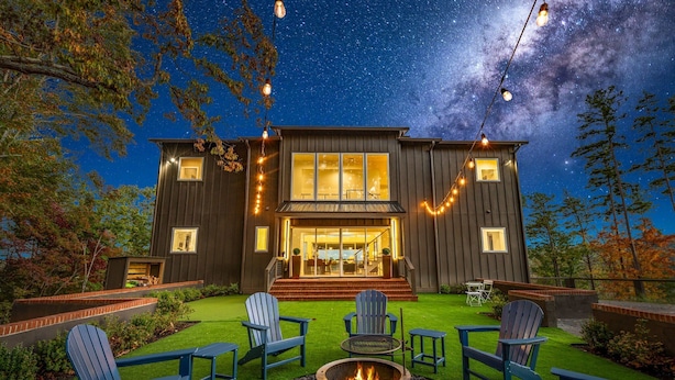 A modern house with a fire pit and outdoor seating, surrounded by a well-maintained lawn and trees. - Blue Ridge Mountain Retreat, Panoramic Views, Game Room, and Hot Tub! (Blue Ridge)