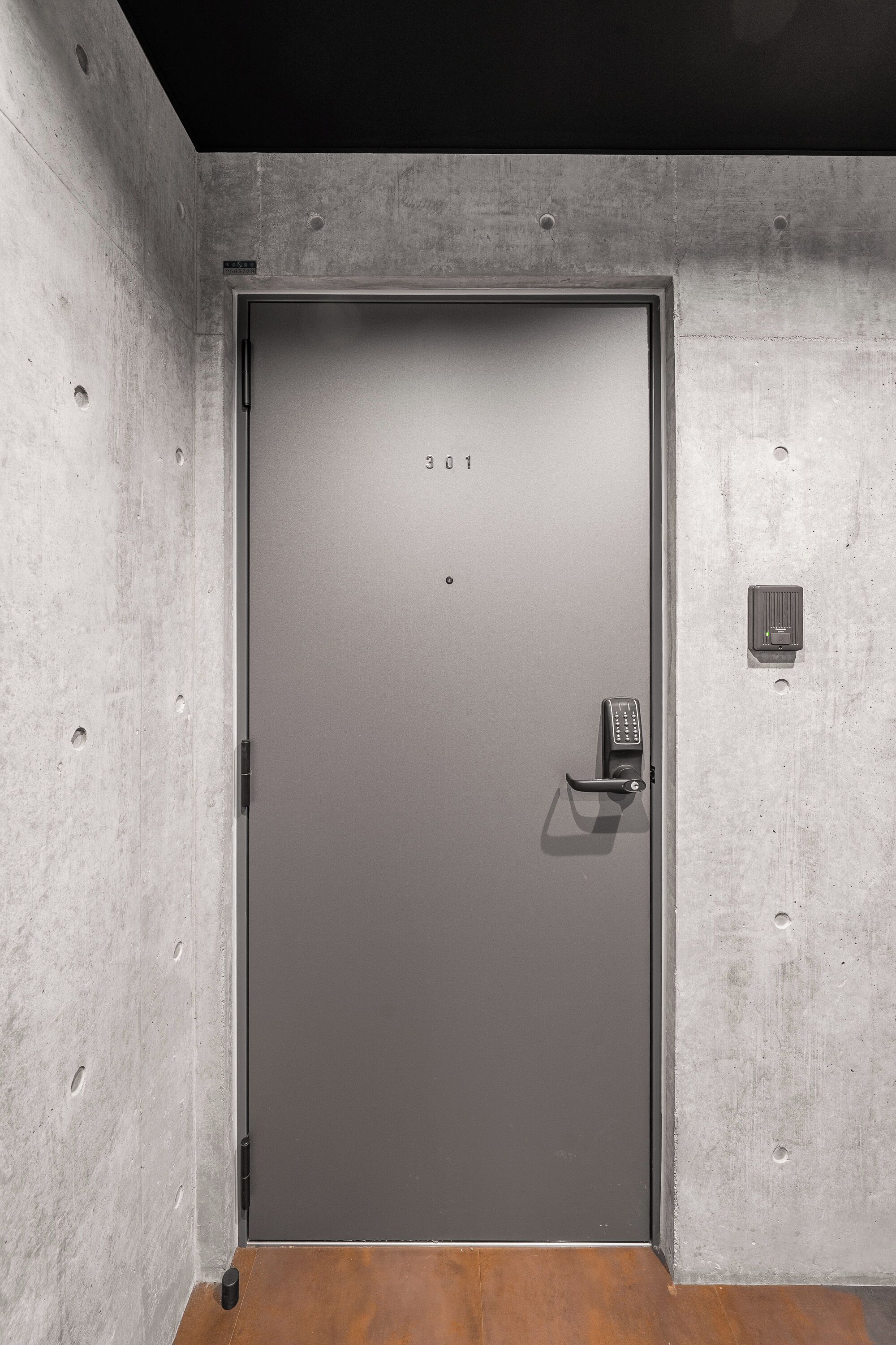 A grey door with a keypad lock, a small control panel, and a number "301" on the door.