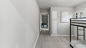 Un pasillo con una litera, una zona de comedor y una puerta que da a otra habitación.