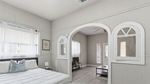 Un dormitorio con una cama grande, un escritorio y un arco que da a otra habitación.