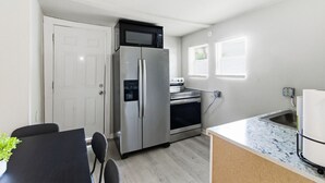 Una cocina compacta equipada con refrigerador, horno, microondas y pileta.