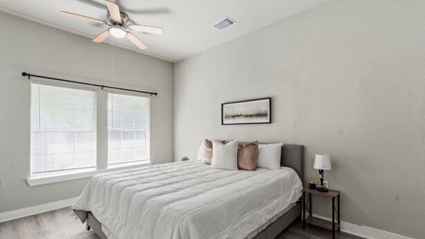A bedroom with a bed, a ceiling fan, a nightstand, a lamp, and a window with blinds. - Bright 2BR Duplex Mins to Downtown San Antonio (San Antonio)
